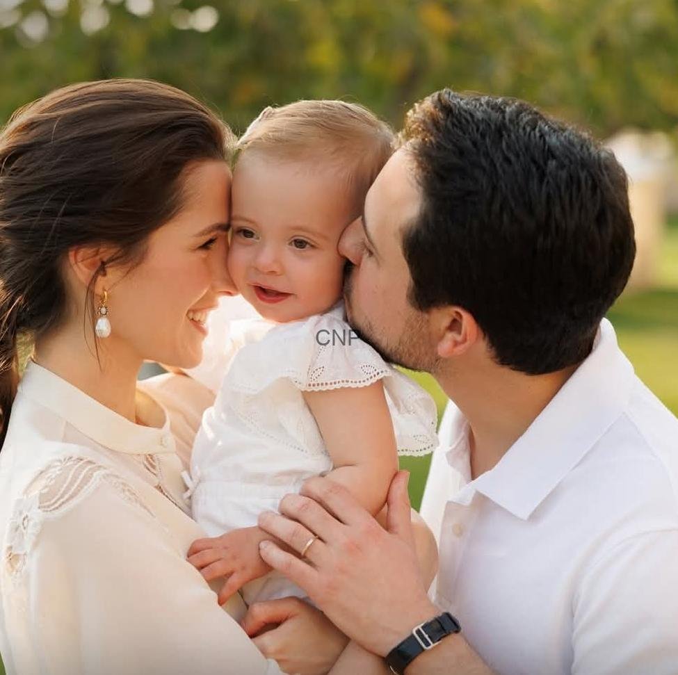 Happy couple kissing their smiling baby outdoors.