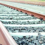 Two parallel railroad tracks run across a gravel bed, fading into the distance.