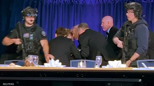 ass - Center News Network Security guards in tactical gear flank a conference table on a stage as suited people lean in for a discussion.