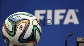 Soccer ball with multicolored panels in front of a blue FIFA backdrop.