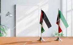 Two small national flags (Nigeria and Italy) stand on a wooden conference table in an office setting.