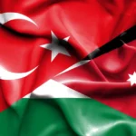 A composite flag image blending Turkey's red crescent and star with Jordanian flag elements (red triangle and black/white/green fields), signaling national solidarity or unity.