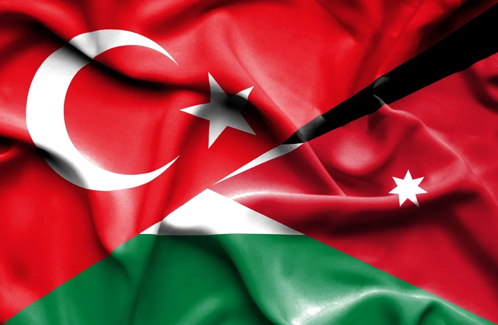 A composite flag image blending Turkey's red crescent and star with Jordanian flag elements (red triangle and black/white/green fields), signaling national solidarity or unity.