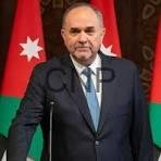 just m - Center News Network Man in a dark suit and blue tie standing in front of a Jordanian flag (red triangle with a white star).