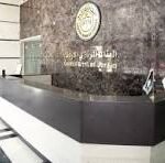 Reception desk in a modern lobby with a dark counter, marble floor, and a circular emblem on the wall behind it; the letters 'CNP' are visible on the glass panel.