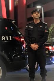 police - Center News Network Uniformed police officer in black attire standing with hands clasped beside a marked police SUV showing '911' at night.