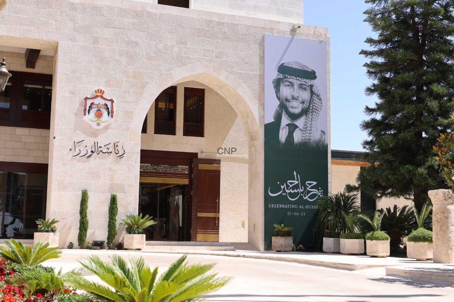 Exterior view of a beige stone building with an arched entrance and a large banner banner featuring a man in a keffiyeh and suit