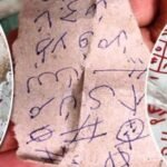 Three torn papers covered in blue and red scribbles, symbols and hash marks, looking like graffiti or cryptic notes photographed up close.