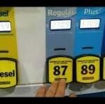 Gas pump with Diesel yellow nozzle on left and blue Regular/Plus/Premium nozzles; price tags show 87, 89, 93, with a hand nearby.