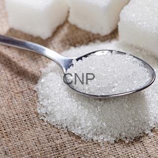 suger - Center News Network Spoon scooping white granulated sugar on a burlap surface with sugar cubes in the background.