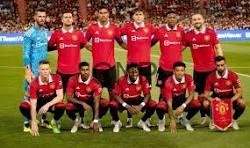 united - Center News Network Soccer team in red jerseys posing for a group photo on the field with a stadium full of fans behind them.