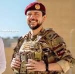 Smiling soldier in camouflage and maroon beret holds a large trophy during an award ceremony.