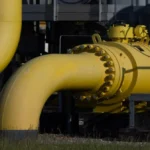 Yellow industrial pipeline with bolted flange connections at a processing facility, close-up view