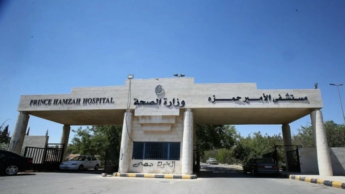 Entrance to Prince Hamzah Hospital with a stone gate and Arabic signage, cars parked in the driveway.