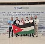 Group of people on stage holding a Jordan flag during the closing ceremony of the 2nd International Olympiad in Artificial Intelligence.