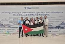 Group of people on stage holding a Jordan flag during the closing ceremony of the 2nd International Olympiad in Artificial Intelligence.