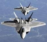 air - Center News Network Two gray military fighter jets fly in close formation over a mountainous landscape, viewed from above.