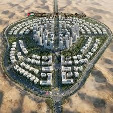 Aerial view of a scale model of a circular planned city with a dense central core and surrounding ring of buildings in a desert landscape.