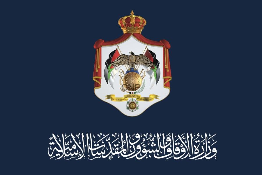 Official government crest on a dark blue background, featuring a crowned shield with an eagle, flags, and Arabic script beneath.