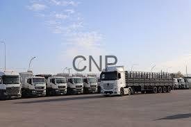 conv - Center News Network Row of white trucks and trailers parked in a large open lot.