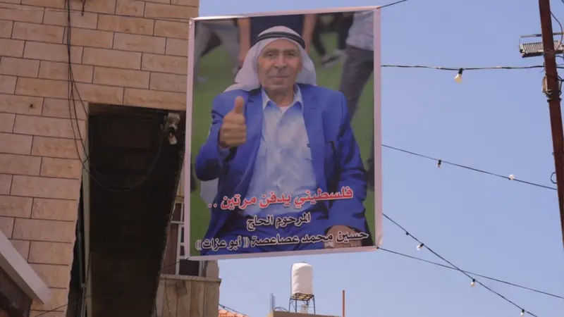 daf - Center News Network Campaign banner showing a man in a blue suit giving a thumbs-up, mounted on a street with Arabic caption at the bottom.