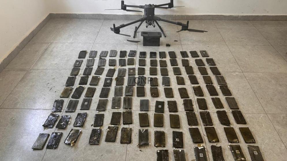 dru - Center News Network Quadrotor drone on a tiled floor above dozens of black smartphones laid out in a grid as evidence.