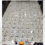 Rows of small white evidence bags laid out on a light tiled floor, each labeled with the number 1, with tools visible in the foreground.