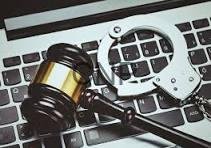 Gavel and handcuffs on a laptop keyboard, symbolizing legal action against cybercrime or tech-related crime.