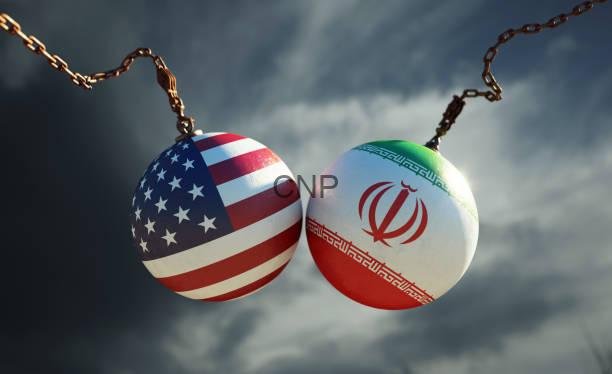 Two chained spheres painted with the US flag and the Iranian flag against a cloudy sky, symbolizing US–Iran ties or tension.