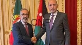 jopo - Center News Network Two men in suits shake hands in a formal room with flags behind them.