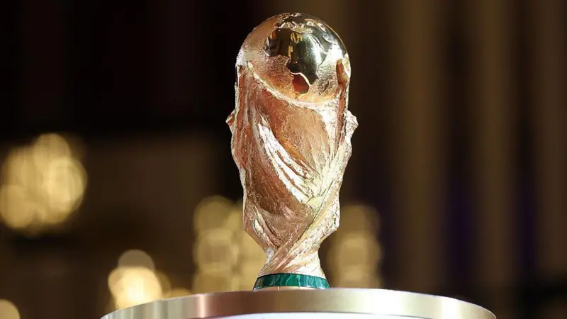 kas - Center News Network FIFA World Cup trophy gleaming gold on a pedestal with a blurred background, ready for presentation.