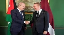 lajtdh - Center News Network Two men in suits shake hands in front of flags during a formal meeting.