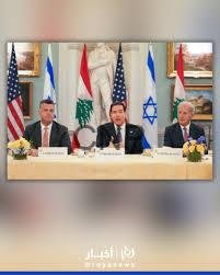 Three diplomats seated behind a conference table with microphones, flanked by US, Lebanese, Japanese, and Israeli flags in the background for a formal meeting.
