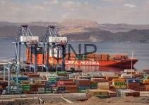 Port scene with colorful shipping containers and large cranes unloading a cargo ship on a calm sea, in the background left.