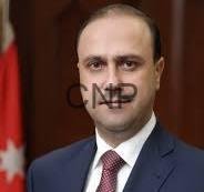 mom - Center News Network Portrait of a man in a navy suit and red tie, with a Turkish flag in the background.