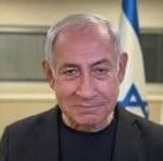 Older man with white hair in a dark suit, standing in front of flags; 'CNP' watermark across his face.