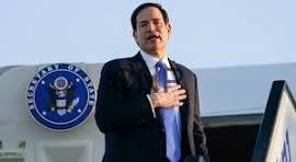 Man in a dark suit giving a speech at a podium, hand over heart, with a government seal visible in the background.