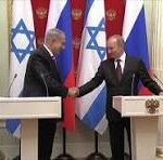 Two male political leaders shake hands at a formal press conference, standing at podiums with Israeli and other national flags behind them.