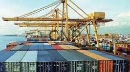 sadd - Center News Network Port with stacked shipping containers and a large gantry crane over a cargo ship in the background at a busy harbor.
