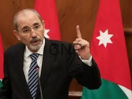 safa - Center News Network A man in a suit speaks at a podium, raising his index finger, with the Jordanian flag in the background.