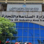 Facade of a government building showing the Ministry of Industry and Trade sign in Arabic and English, with blue glass windows and surrounding trees.