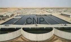 Rooftop solar panels on a low industrial building in a desert, with circular vent structures in the foreground and a blue sky above.