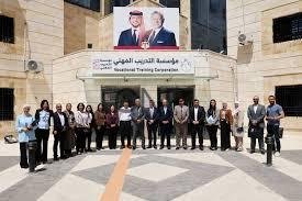 tadreeb - Center News Network Group of about 25 people posing in front of a beige institutional building with an Arabic banner and a large poster of two men above the entrance, in a courtyard area with a patterned ground.