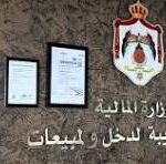 Signage on a wall for the Ministry of Interior, featuring an official crest and framed certificates alongside Arabic text in the background.