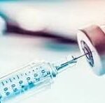 Close-up of a syringe with a needle and vial in soft focus, with the letters CNP overlayed.