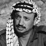 Black-and-white portrait of a man wearing a checkered headscarf and dark shirt, looking to the left.