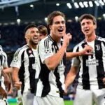 Juventus players celebrate a goal on the pitch in black-and-white striped jerseys.