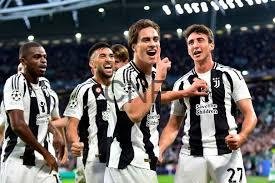Juventus players celebrate a goal on the pitch in black-and-white striped jerseys.