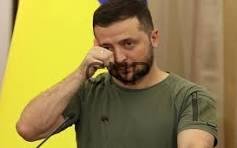 zel - Center News Network Man in a green t-shirt talking on a mobile phone with a yellow backdrop behind him.