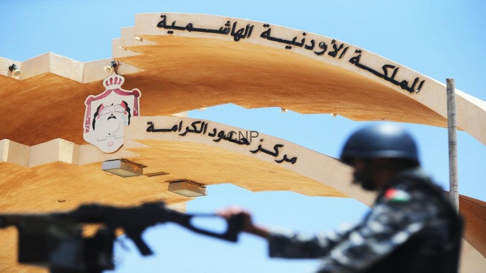 Security checkpoint at Jordan's border with a soldier in the foreground and the Hashemite Kingdom of Jordan arch in Arabic above.